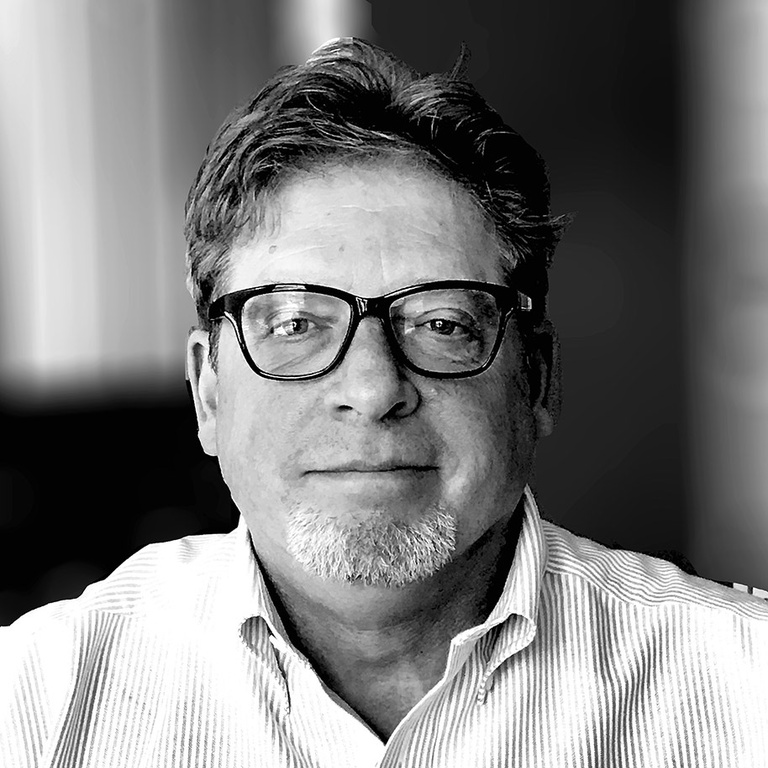 Black and white photo of Phillip Round wearinga  collared shirt and glasses
