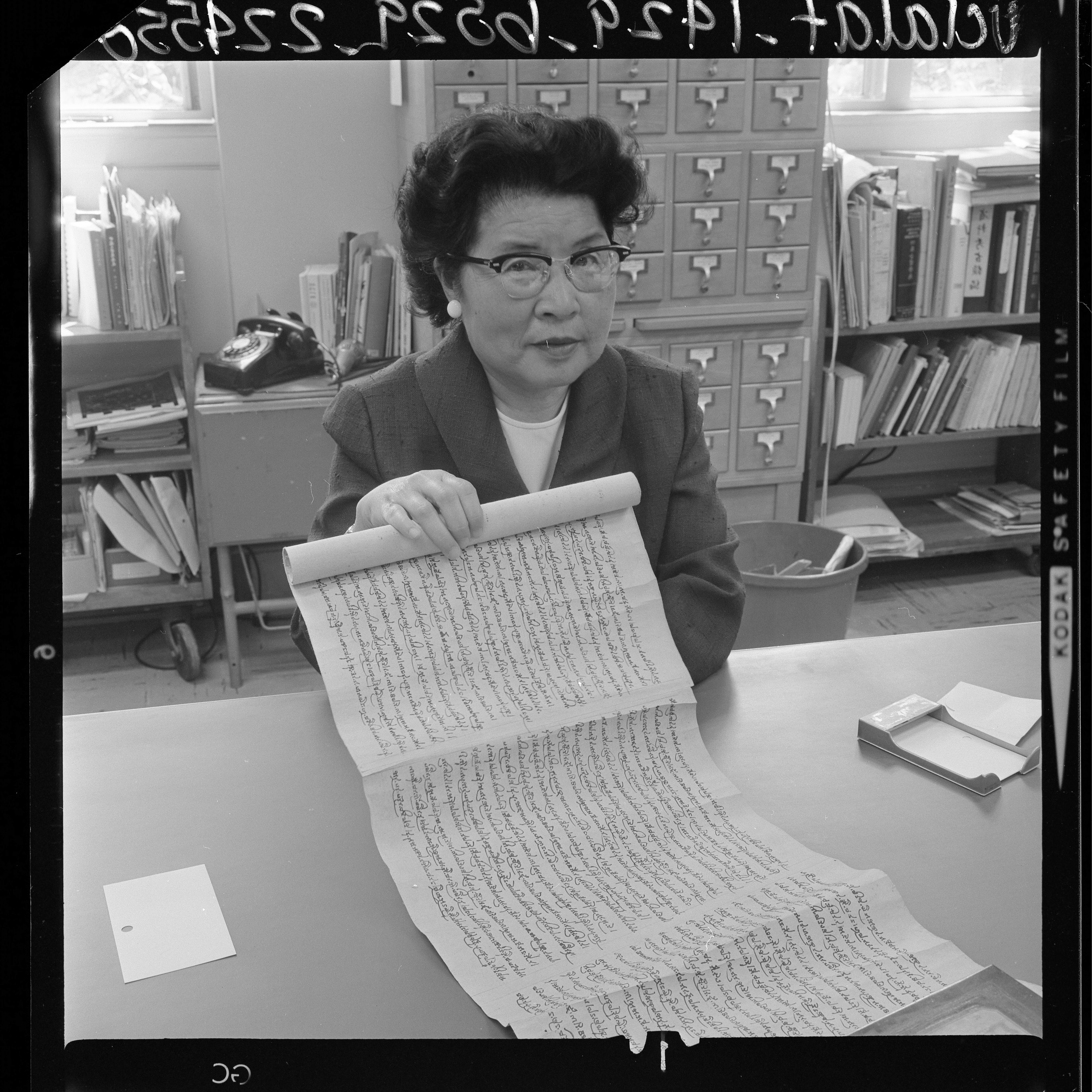“Mrs. Man Hing Mok, head of UCLA Oriental Library holding ancient Tibetan manuscript-scroll, 1964” (Los Angeles Times, 1964). © UCLA Library Special Collections.